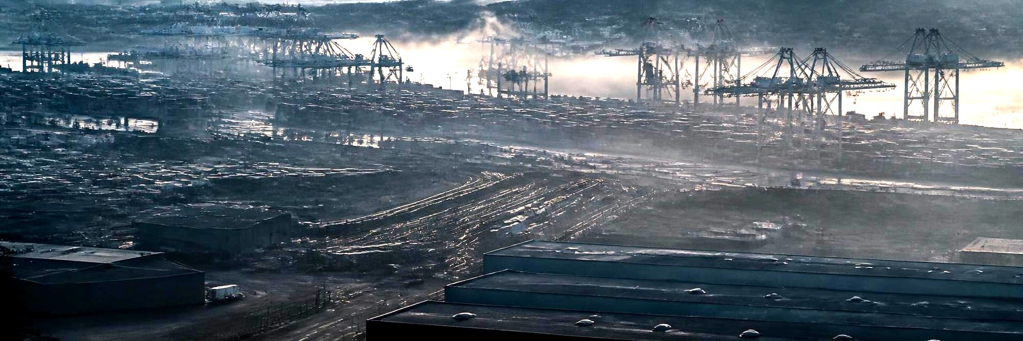 Aerial view of a port and logistics landscape with container cranes and rail lines at dawn